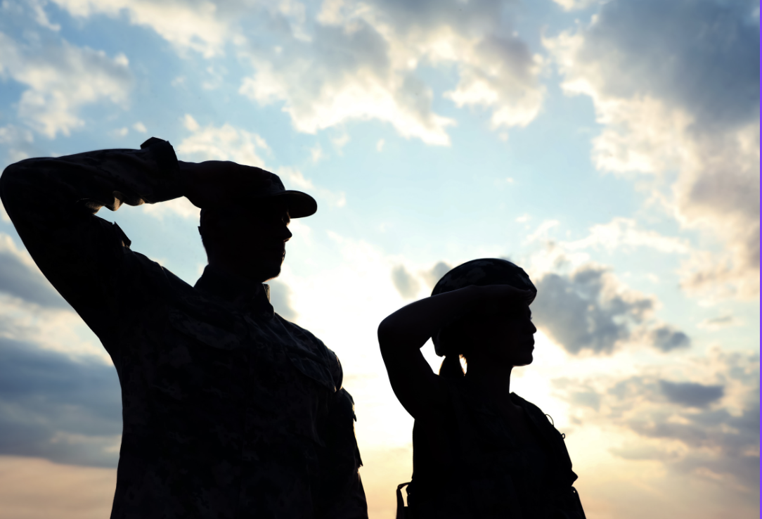 Two veterans saluting, symbolizing the commitment to improving healthcare access and support for veterans.